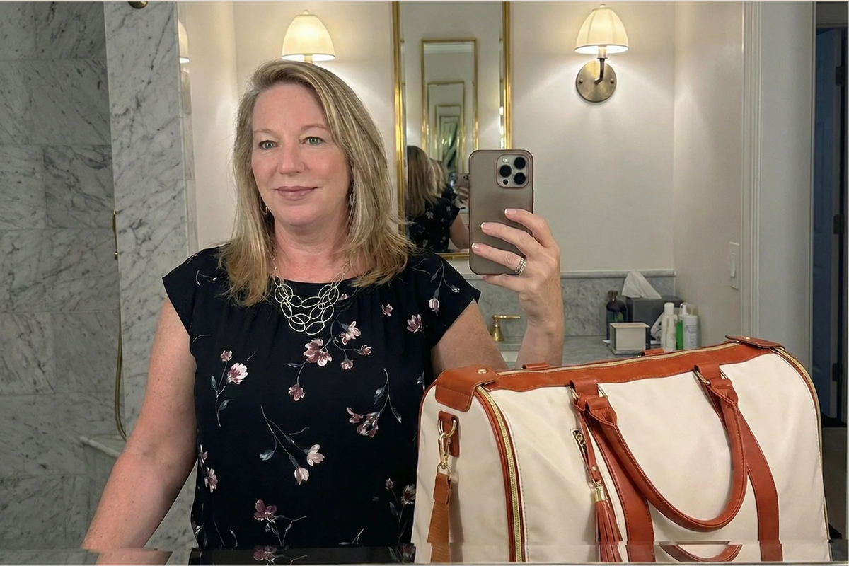 Katherine takes a mirror selfie in a hotel bathroom with her cream and tan Luhxe bag